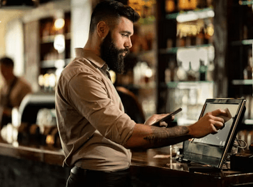 A bar owner taking a card payment on a Surge POS tablet
